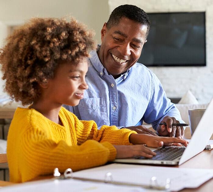 A father helping his daughter with school work on a laptop